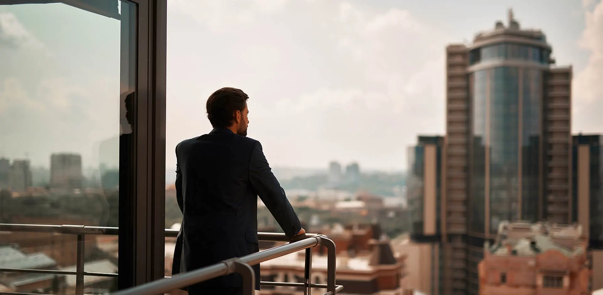 Business professional on the balcony of an office building looking out over the rest of the city