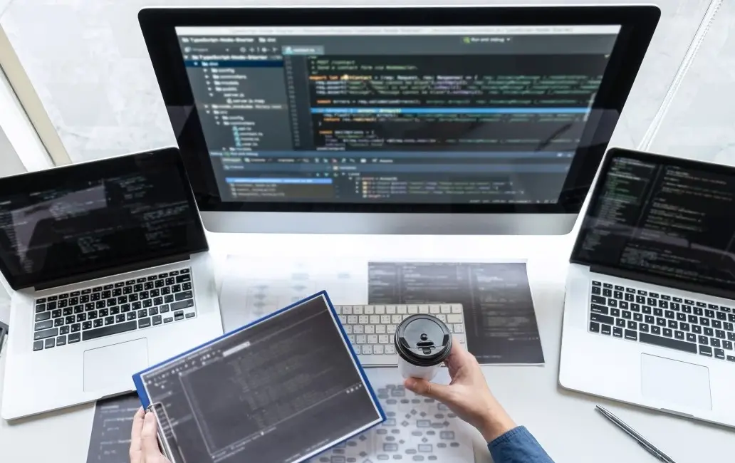 Photo of a developer writing code using multiple machines