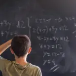 Poto of a schoolboy solving a problem on a blackboard