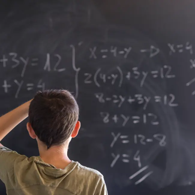 Poto of a schoolboy solving a problem on a blackboard