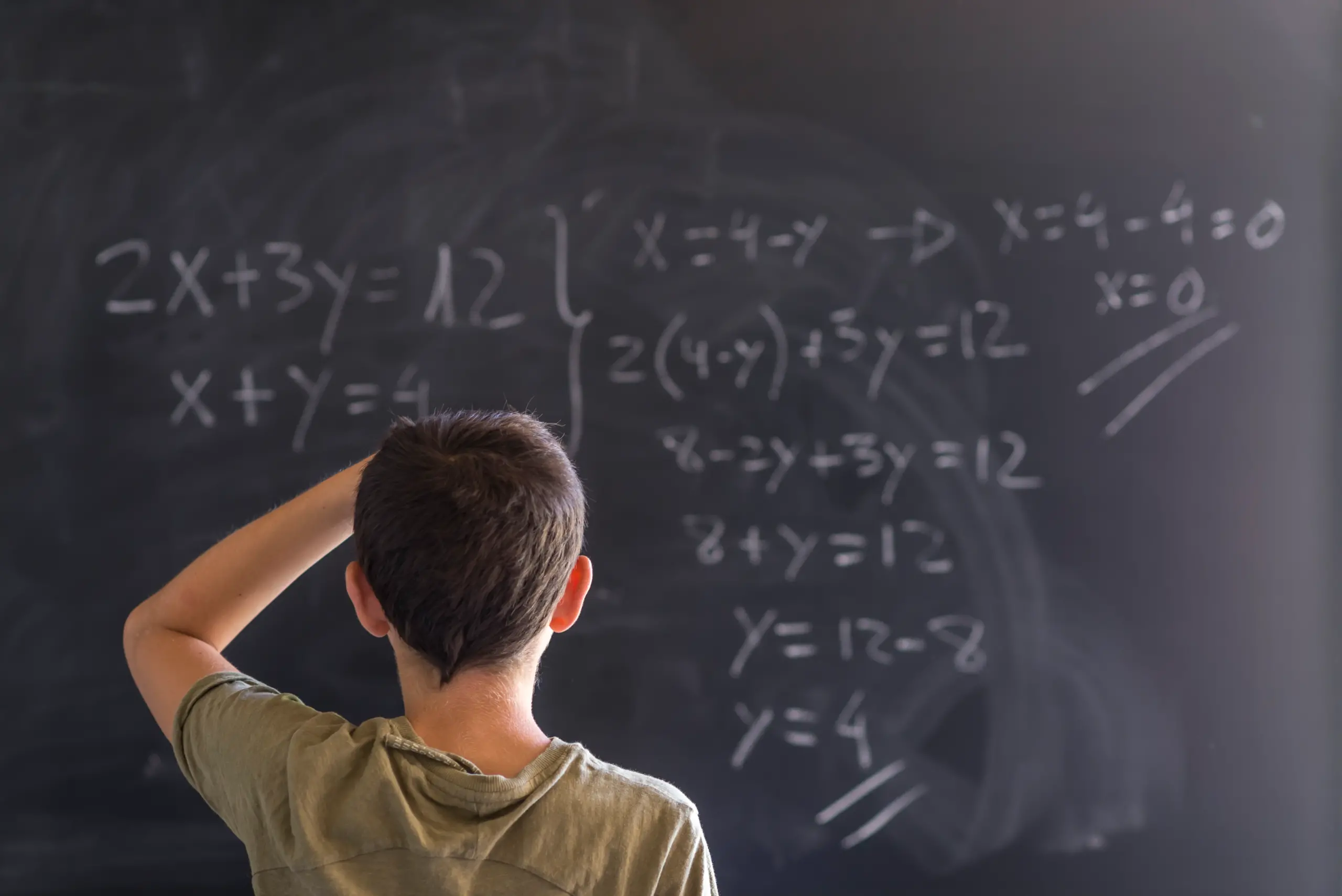 Poto of a schoolboy solving a problem on a blackboard